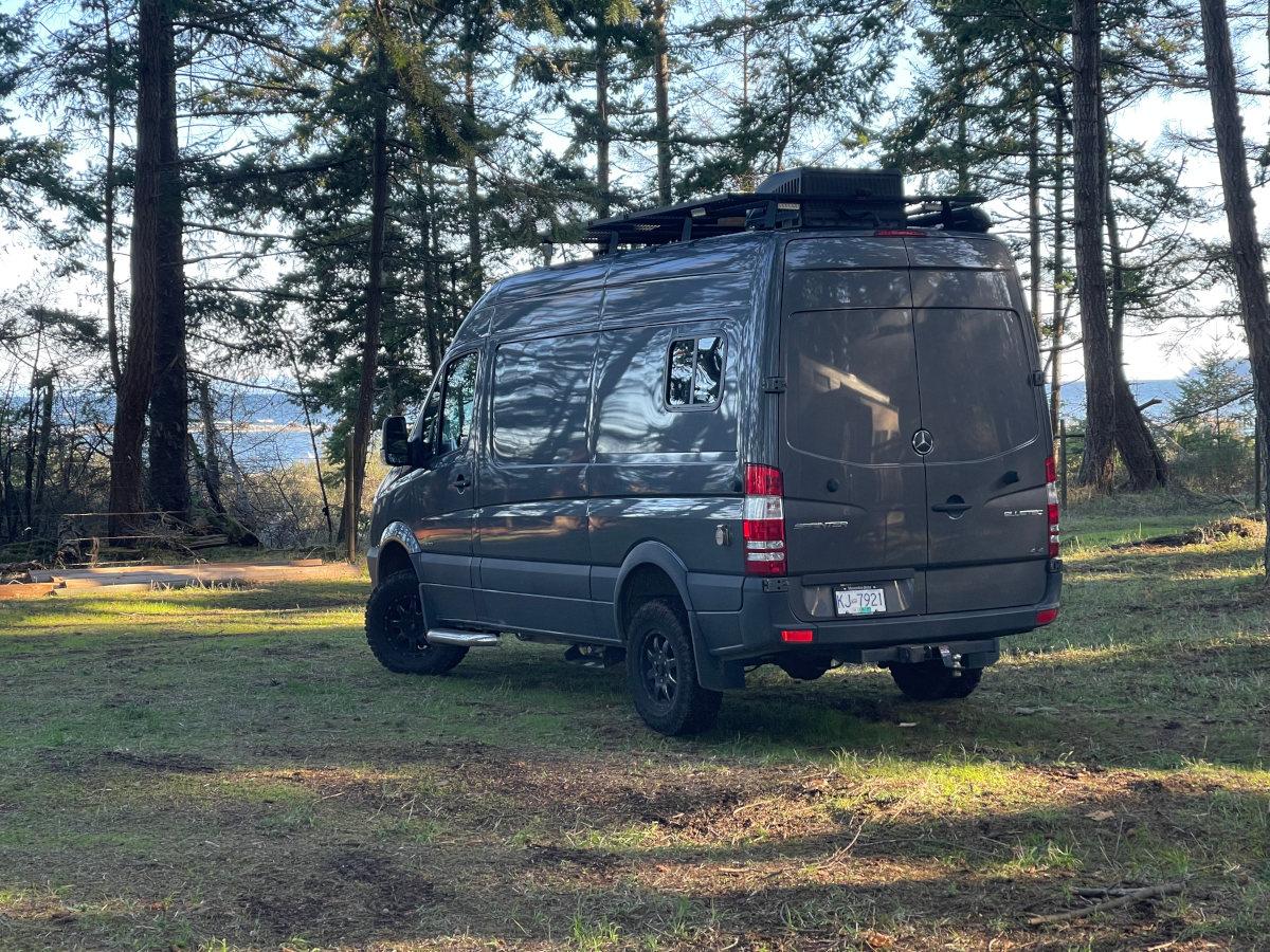 Custom grey Sprinter Van conversion parked at beach